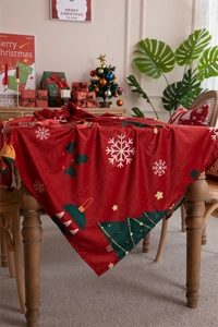 Detail of red Christmas tablecloth with snowflake and tree patterns on a festive wooden table