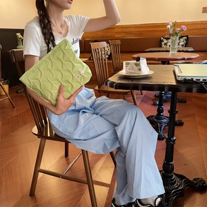 Detail of light green pleated fabric makeup bag with rich texture in a cafe setting