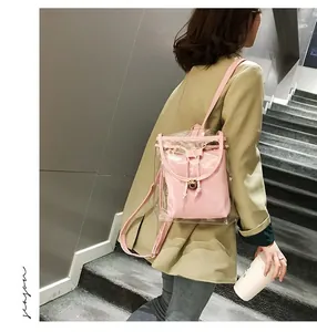 Detail of pink transparent PVC mini backpack with drawstring and metal buckle on a model