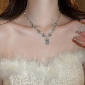 Close-up of a silver teardrop crystal necklace featuring shimmering rhinestones on a model
