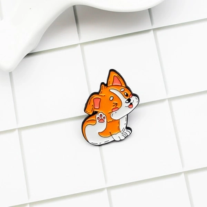 Close-up of a cute orange and white Corgi enamel pin badge with polished metal edges