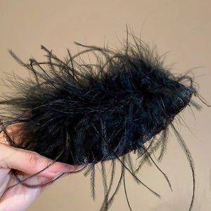 Detailed shot of fluffy black feather tassel hair clip with elegant acrylic texture