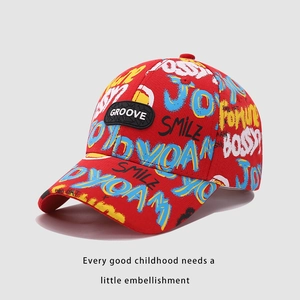 Détail de casquette baseball enfant rouge avec imprimé graffiti et écusson GROOVE