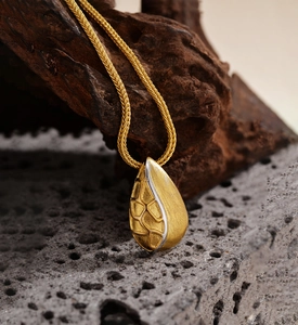 Macro shot of Italian-style gold brushed pendant with honeycomb texture and woven chain