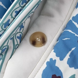 Macro d'un bouton marron sur veste en coton avec imprimé floral bleu et blanc pour femme