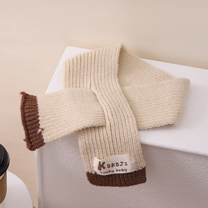 Detail eines Grobstrickschals in Creme und Braun mit gewebtem Baby-Aufnäher-Design