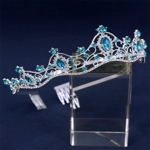 Close-up of bridal crown featuring blue gemstones and silver metal on a clear stand