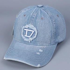 Dettaglio macro della toppa ricamata con lettera D e tessuto denim lavato del cappello