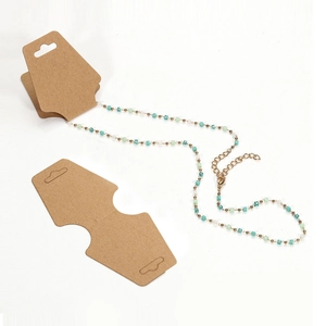Gold chain necklace with turquoise and white beads on kraft paper display cards