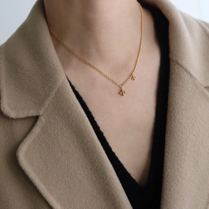 Detail of a minimalist gold cross pendant and layered chain necklace on a model