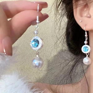 Bowknot pearl drop earrings with blue zircon in silver finish shown on a model