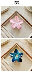 Detailed close-up of plumeria hair claws in pink marble and teal blue cracked patterns