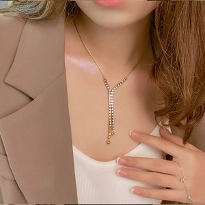 Elegant gold Y-shaped necklace with sparkling rhinestones worn by a model in a brown suit