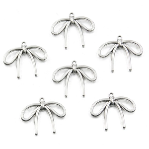 Flat lay of six silver hollow bow alloy pendants for DIY necklace and jewelry making
