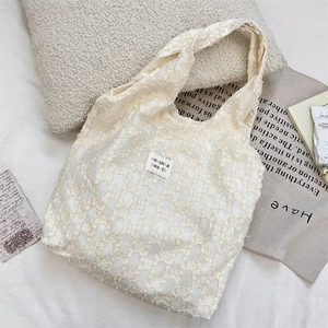 Close-up of beige jacquard tote bag with textured feather yarn fabric and brand label