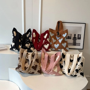 Multiple colorful knitted tote bags with heart patterns displayed on stairs