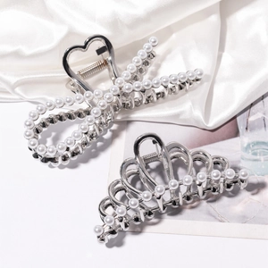 Close-up of silver metal hair claws with white pearls on silk background