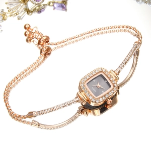 Square quartz watch with rose gold chain bracelet and rhinestone bezel on mirror background