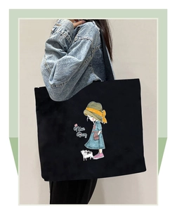 Close-up of black canvas tote bag with cartoon girl and cat illustration and Nice Day text