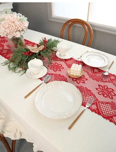 Close-up of red Christmas lace table runner with intricate hollow patterns and tassels