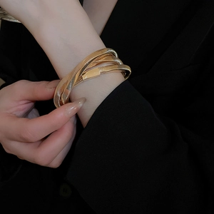 Detailed view of a multi-layer golden snake bone texture cuff on a black suit sleeve