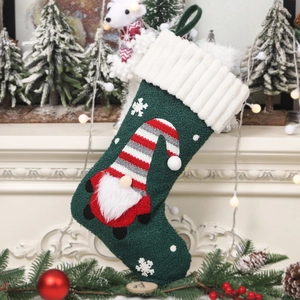 Chaussette de Noël en peluche verte avec gnome suspendue à une cheminée décorée