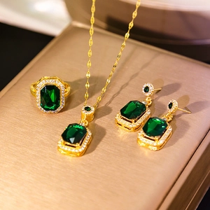 Macro shot of emerald green jewelry set with necklace, earrings and ring in gold finish