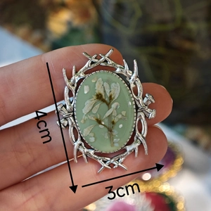 Detail shot of handmade vintage oval brooch showing 4x3cm size with dried flowers
