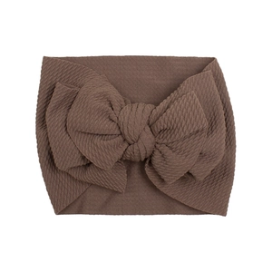 Detail of soft brown textured fabric baby headband featuring a large bow on white background