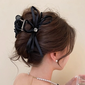 Elegant black silk satin bow hair claw with crystal detail on model's dark brown hair