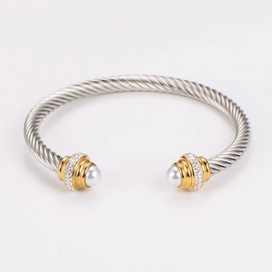 Macro detail of twisted cable bangle with pearl and pavé stone inlays on silver band