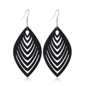 Macro detail of black hollowed-out wooden earrings with layered geometric leaf pattern
