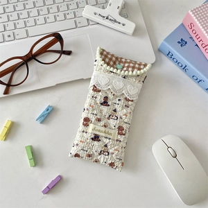 Close-up of quilted cream eyeglass pouch with dog print and lace trim on office desk