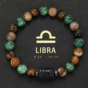 Detail of Libra zodiac bracelet with tiger eye beads on a dark textured background
