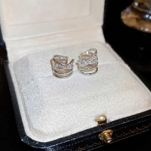 Crossed multi-layer silver ear bone clips with zircon stones on a jewelry box