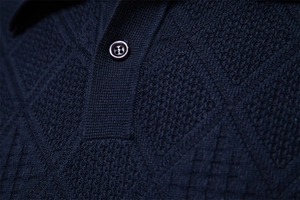Macro shot of dark blue knit polo shirt collar showing fine texture and single button