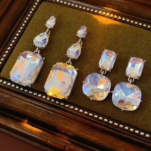 Close-up of luxury rhinestone drop earrings on green velvet tray with iridescent gems