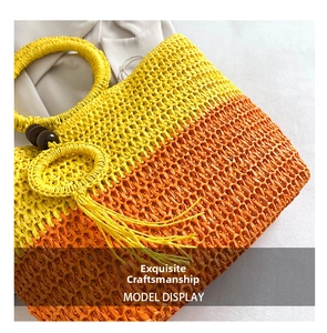 Close-up of a gradient woven straw bag with circular handles and tassel charm detail