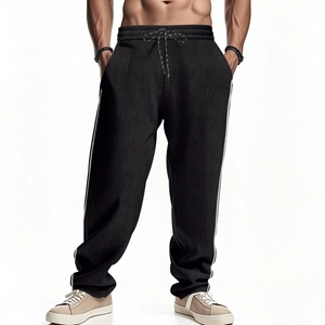 Detail of men's black corduroy trousers featuring white side stripes and drawstring waist