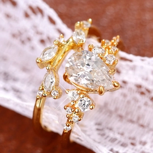 Macro shot of gold tone wedding ring set with pear cut stone and leaf branch band