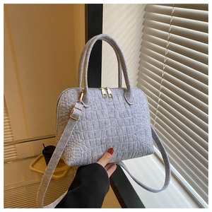 Detailed shot of grey crocodile embossed felt shell bag with gold hardware and handles