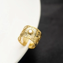 Macro shot of gold-plated lace cutout ring with a white round shell inlay centerpiece