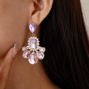 Detailed view of vintage gold earrings with purple crystals and pink drop gems on a model