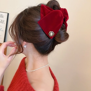 Vue détaillée de la pince à cheveux en velours rouge avec perles sur un chignon élégant