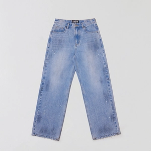 Détail d'un jean en denim délavé bleu clair avec taches de peinture et étiquette