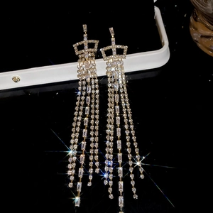 Macro detail of crown-shaped silver earrings with long tassels and sparkling zircon stones