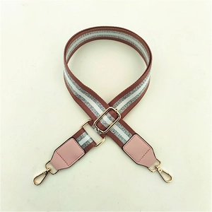 Close-up of adjustable striped fabric strap with pink leather ends and gold-tone hooks
