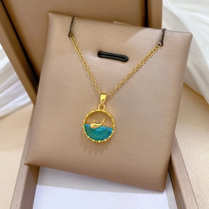 Detailed view of gold whale pendant with blue-green gemstone in a gift box