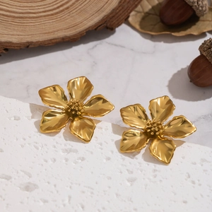 Elegant gold vintage flower earrings on a marble base with a natural background