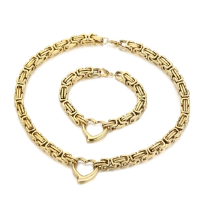Gold Byzantine necklace and bracelet jewelry set with hollow heart pendant on white background